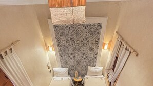 A room with two beds, a patterned wall, a small table with a lamp, and a wooden staircase. - Riad Minami (Marrakech)