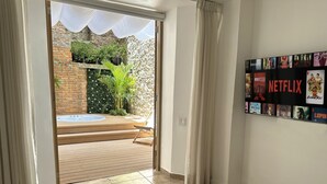 A room with a view of a garden, a wooden deck, and a wall with Netflix posters. - Unique Apartment with Jacuzzi (Ciudad de Panamá)