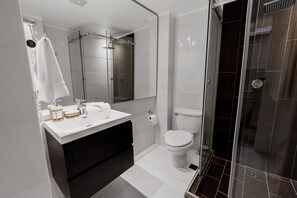 A modern bathroom with a white vanity, a glass shower enclosure, and a toilet. - Unique Apartment with Jacuzzi (Ciudad de Panamá)