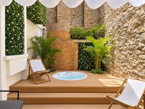A wooden deck with a hot tub, surrounded by stone walls and greenery. - Unique Apartment with Jacuzzi (Ciudad de Panamá)
