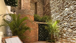 A wooden deck with a hot tub, surrounded by stone walls and greenery. - Unique Apartment with Jacuzzi (Ciudad de Panamá)