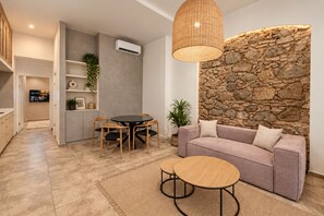 Una sala moderna con una pared de acento de piedra, una mesa de comedor redonda y un sofá con cojines.