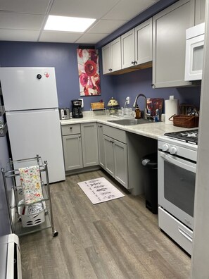 Una cocina con refrigerador, estufa, lavaplatos y alacenas.