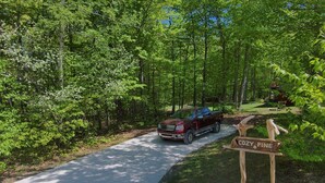 A red pickup truck parked on a gravel path in a wooded area with a wooden sign reading "COZY PINE". - The Cozy Pine, where your Grand Marais Retreat Begins! (Grand Marais)