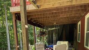 A covered outdoor seating area with a table and chairs, surrounded by gravel and greenery. - The Cozy Pine, where your Grand Marais Retreat Begins! (Grand Marais)