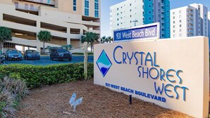 A sign for Crystal Shores West Boulevard with a parking lot and buildings in the background.