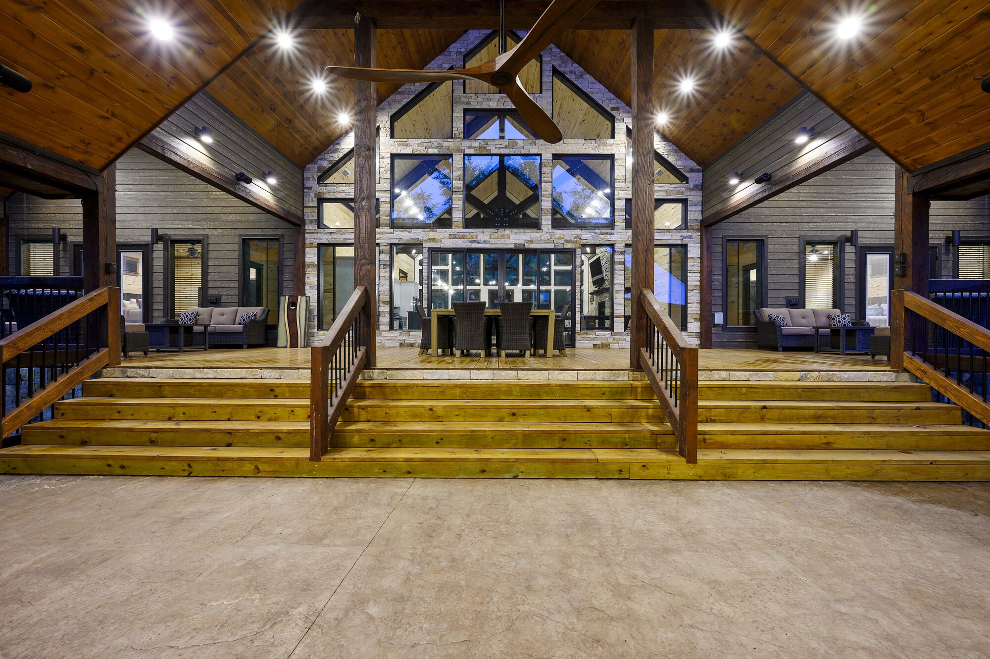 A spacious interior with a central staircase leading to a balcony, surrounded by wooden beams and stone walls.