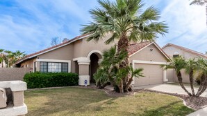 A residential house with a beige exterior, a tiled roof, and a front yard with a palm tree and a hedge. - 4 Bedroom Incredible Backyard with Pool! (Glendale)