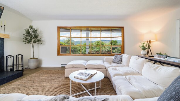 A modern living room with a large window, a fireplace, a sofa, and a coffee table.