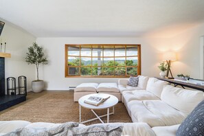 Una sala de estar moderna con un ventanal grande, una chimenea, un sofá y una mesita de centro.