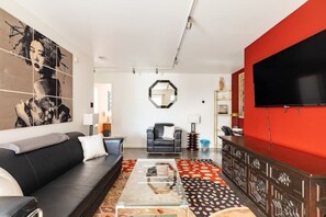 Relax in this stylish living room with a black leather sofa, glass coffee table, and patterned rug.