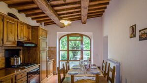 Une cuisine rustique avec des meubles de rangement en bois, un poêle et une table à manger pour quatre personnes.