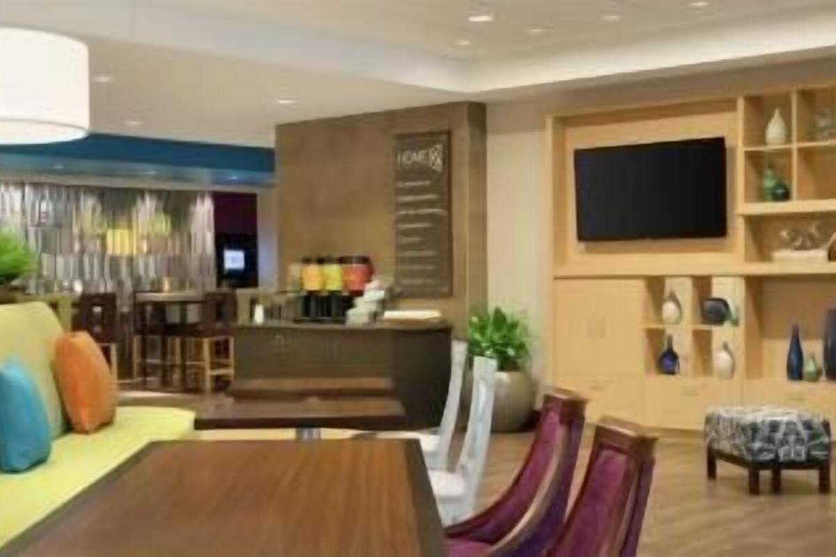 A modern hotel lobby with a seating area, a bar, and a television.