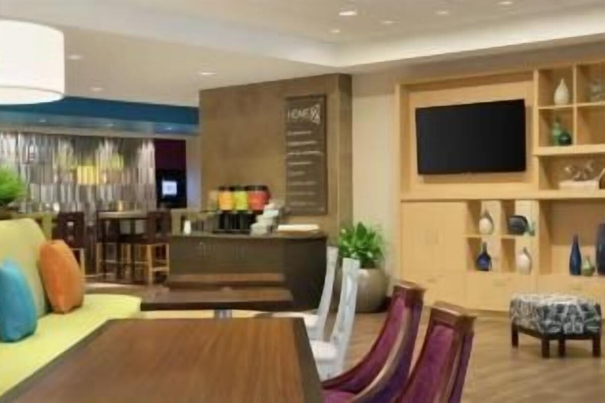 Eine moderne Hotelhalle mit Sitzgelegenheit, einer Bar und einem Fernseher.