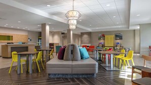 Un moderno vestíbulo de hotel con una zona de estar central, una recepción y un comedor.
