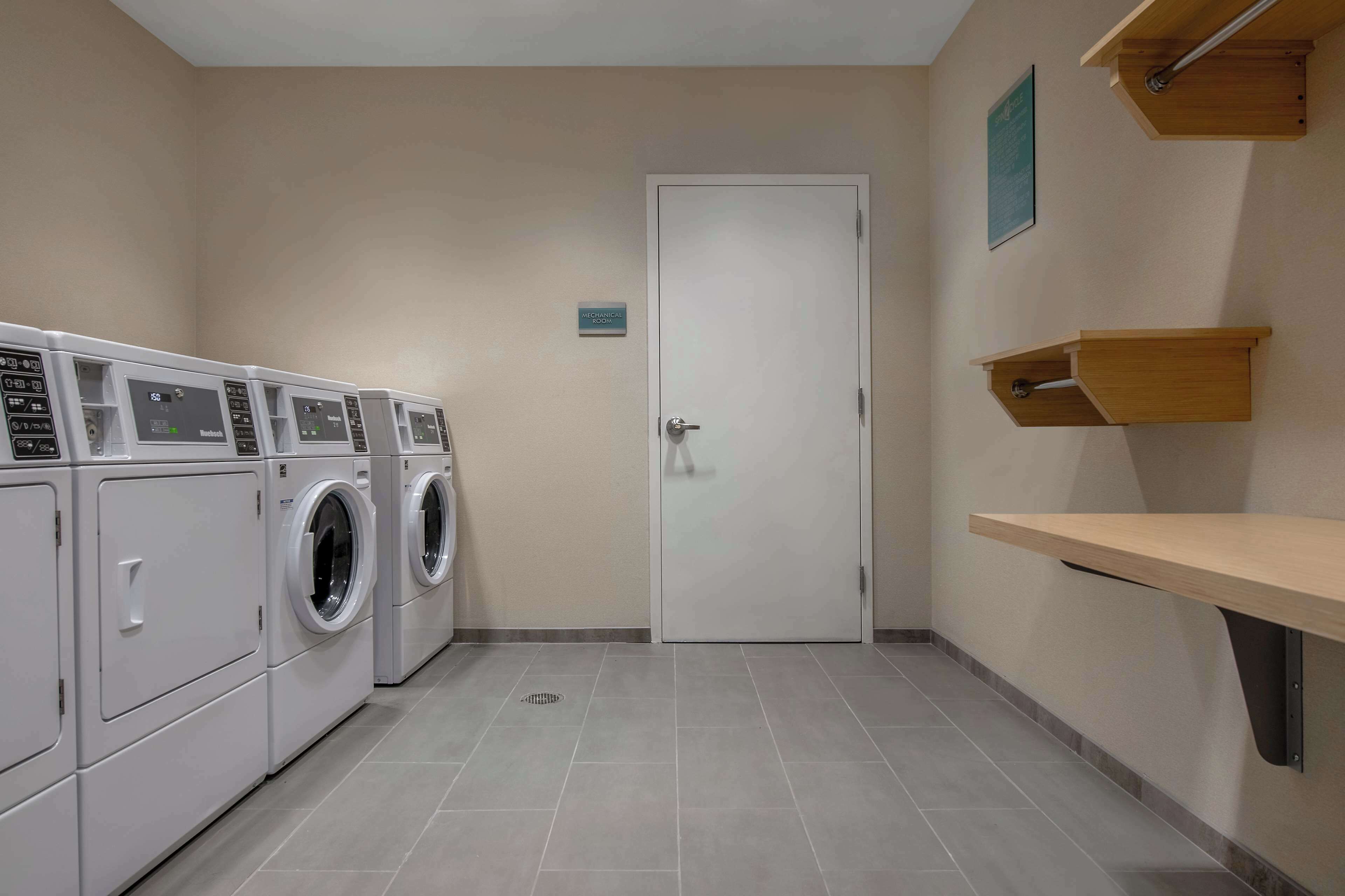 Een wasserij met meerdere wasmachines, een deur en een klein plankje.