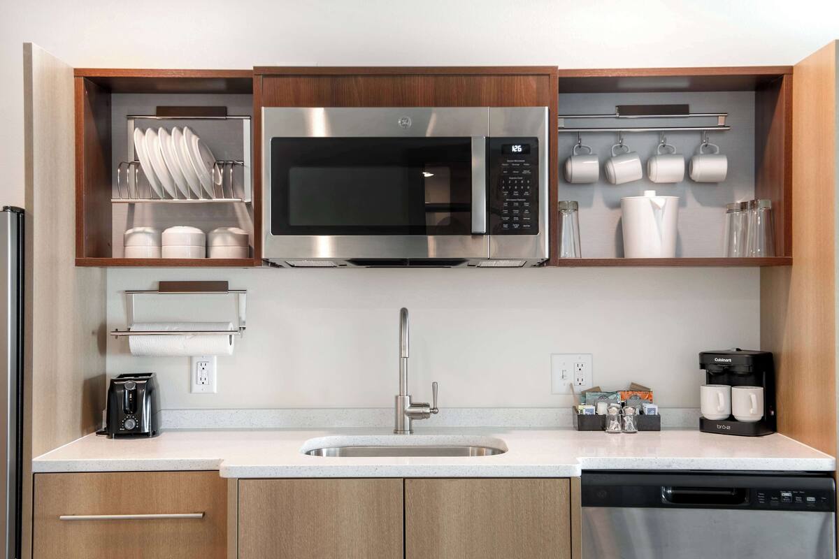 A compact kitchen with a built-in microwave, a coffee maker, and a dish rack.