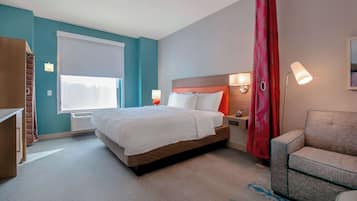 Quarto de hotel com cama, abajures, um sofá e uma janela com persianas.