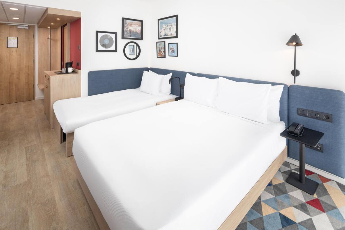 A hotel room with a large bed, bedside tables, a desk, and a lamp.