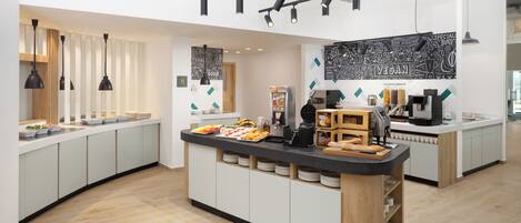 A modern kitchen area with a central island, white cabinets, and a chalkboard wall with doodles.