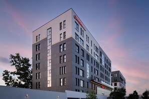 A modern hotel building with a prominent 'Hampton' sign, multiple floors, and a flat roof design. - Hampton by Hilton Targu Mures (Targu Mures)