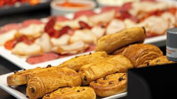 Buffet com diversos alimentos, incluindo doces, carnes e vegetais.
