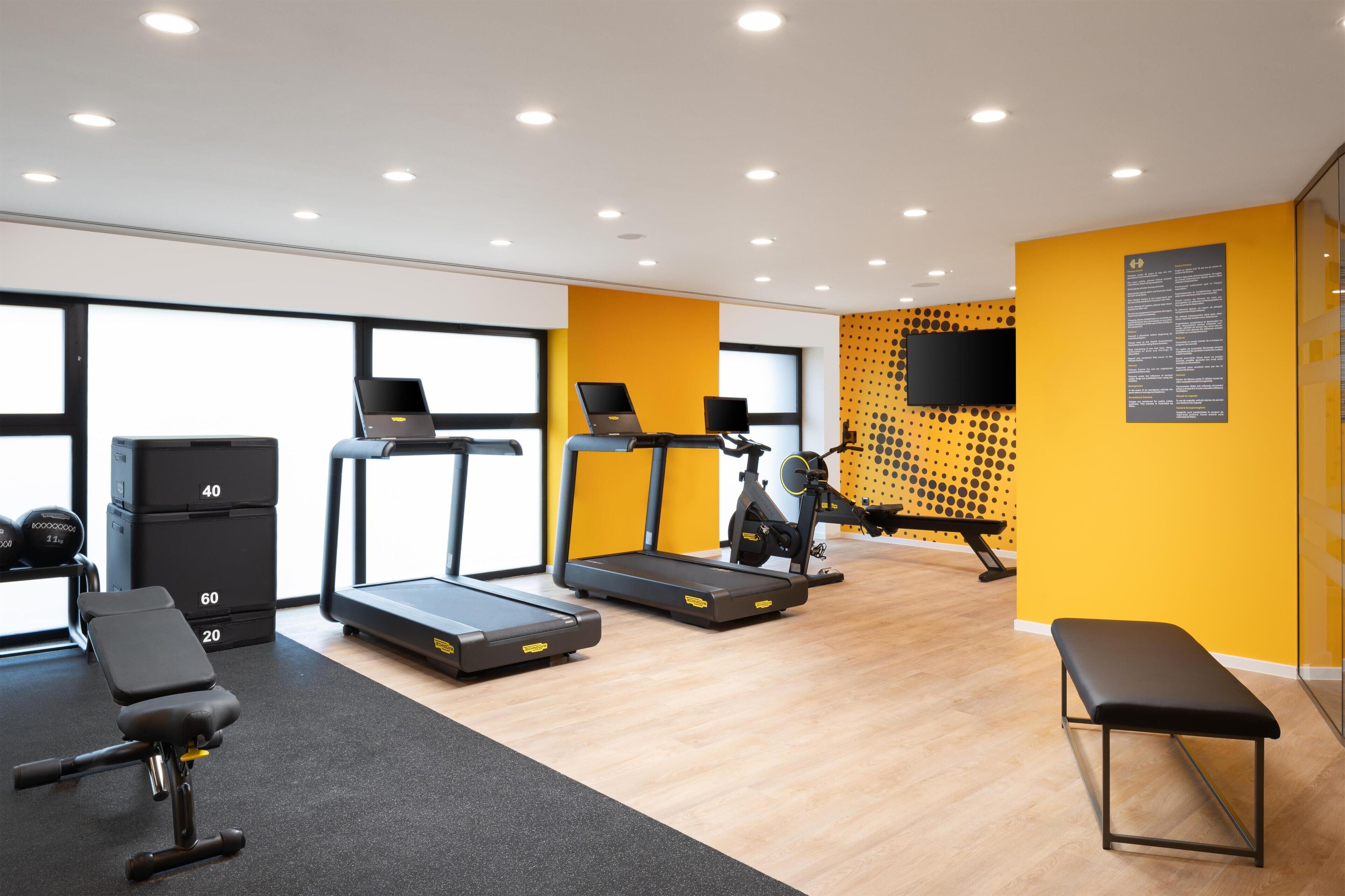 Un gimnasio moderno con cintas de correr, bancos y máquinas de pesas.