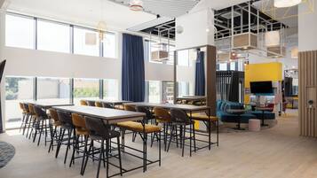 A modern dining area with high ceilings, large windows, and contemporary furniture.