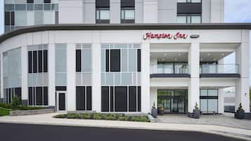 A modern Hampton Inn hotel with a curved facade, large windows, and a prominent entrance with a glass door.