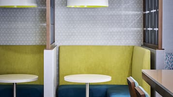Un interior moderno con dos mesas redondas y bancos, un muro con diseño y un biombo decorativo.