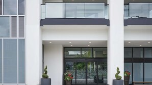 The exterior of Hampton Inn by Hilton with a modern design, featuring a prominent entrance, large windows, and potted plants. - Hampton Inn by Hilton Hamilton (Hamilton)