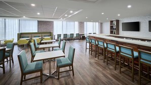 A modern hotel lobby with a bar area, seating arrangements, and a large TV screen. - Hampton Inn by Hilton Hamilton (Hamilton)