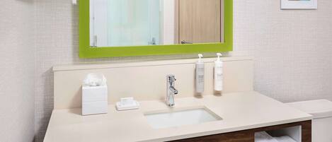 Un baño moderno con un lavabo blanco, espejo con marco verde y un perchero para toallas.