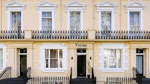 A row of three-story townhouses with a classic architectural style, featuring symmetrical windows and a central entrance labeled "Voyage." - The Voyage Hotel Paddington  (London)