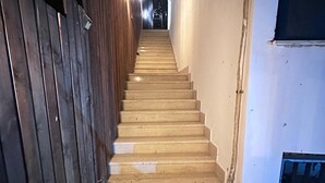 A staircase with wooden steps leading upwards, flanked by a wooden wall on one side and a white wall on the other.