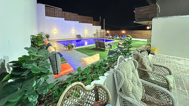 A pool area with lounge chairs and potted plants.