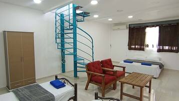 A dormitory room with bunk beds, a spiral staircase, a wardrobe, a desk, and a chair.