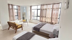 A hotel room with two beds, a desk, and a chair.