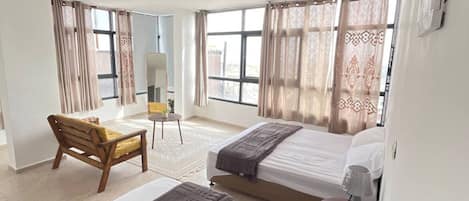 A hotel room with two beds, a desk, and a chair.