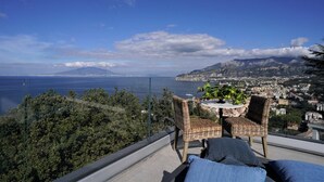 Un balcon agrémenté de meubles en osier, une table avec une plante et une vue sur le paysage urbain.