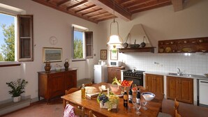 Une cuisine rustique avec des meubles en bois, une table à manger dressée avec de la nourriture et du vin, et une fenêtre donnant sur un paysage arboré.