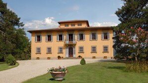 Un grand bâtiment à deux étages, doté d’une façade symétrique, de nombreuses fenêtres avec volets et d’une entrée centrale avec un escalier.