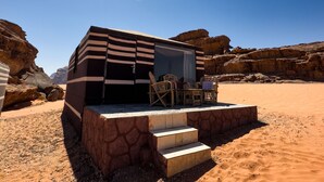 A desert hotel with a flat roof, outdoor seating, and a staircase leading to the entrance. - Rum Crown Camp (Wadi Rum)