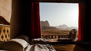 A room with a bed, a chair, and a view of a desert landscape. - Rum Crown Camp (Wadi Rum)