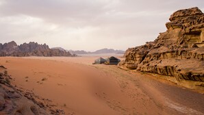 A desert landscape with a building featuring a flat roof and a simple, modern design. - Rum Crown Camp (Wadi Rum)