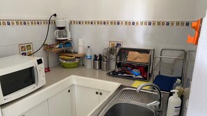 A compact kitchen with a microwave, sink, and various kitchen items. - A 8mn de la Plage, T2 Situé au Centre de Sainte-anne Guadeloupe (SAINTE-ANNE)