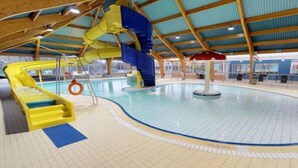En inomhuspool med två vattenrutschkanor, en livboj och en centralt placerad vattenfontän.