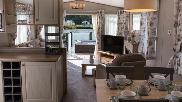 Ett kompakt bostadsutrymme med ett litet kök, en matplats, en tv och utsikt över ett bostadsområde.