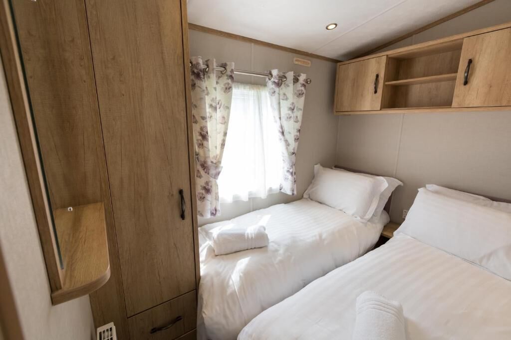 Une chambre avec deux lits, une armoire en bois et une fenêtre avec des rideaux.