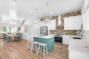 Een moderne keuken met witte kasten, een blauwgroen eiland en roestvrijstalen apparatuur.